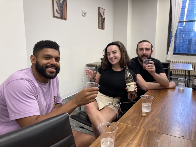 Three people sitting at a table drinking whiskey
